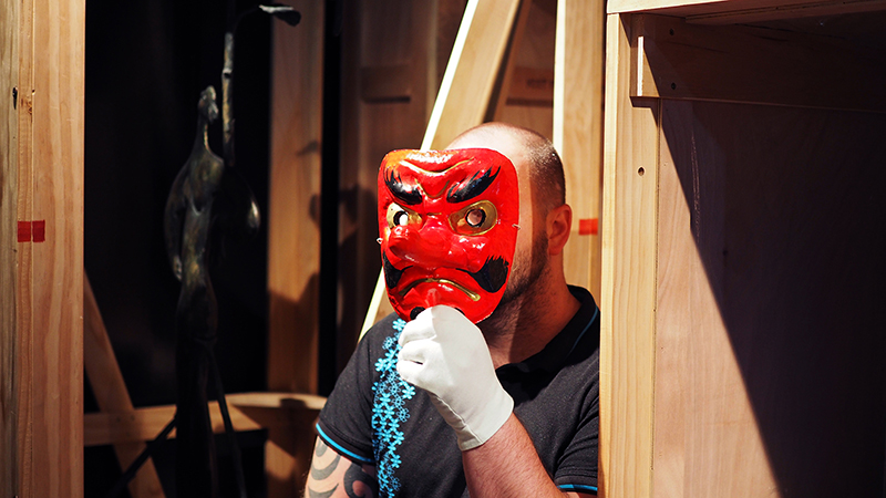 A man wearing a bright red Japanese theatre mask