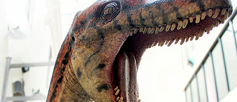 A slim dinosaur roars at the camera