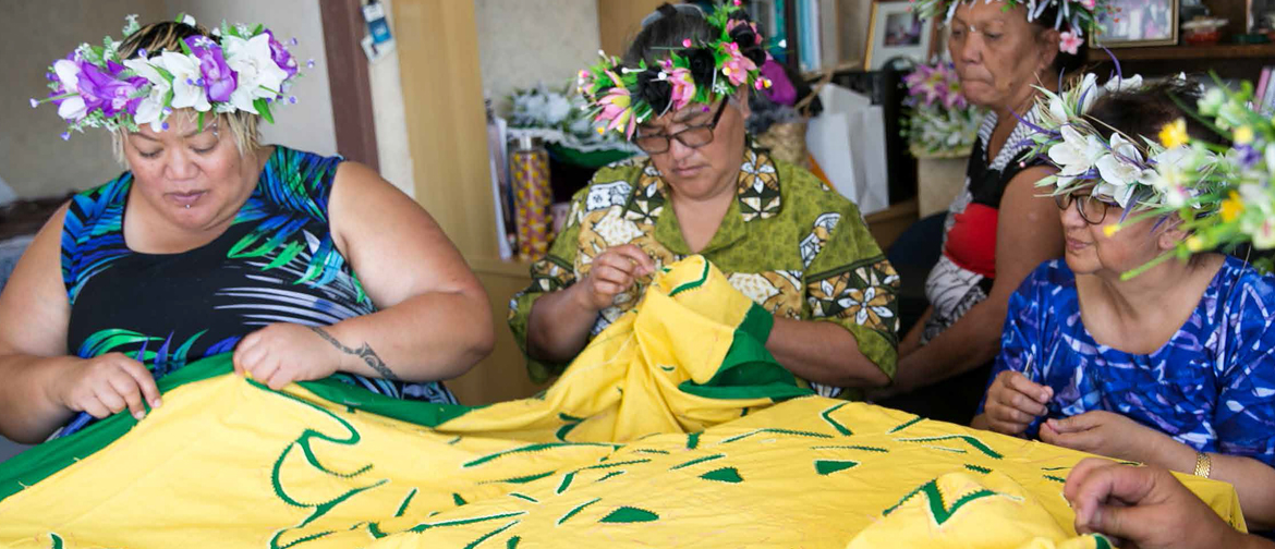 A trio of Pasifika women work together on a large yellow quilt