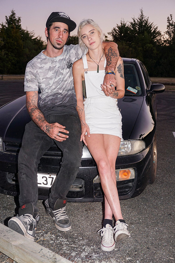 Young couple pose leaning on a car