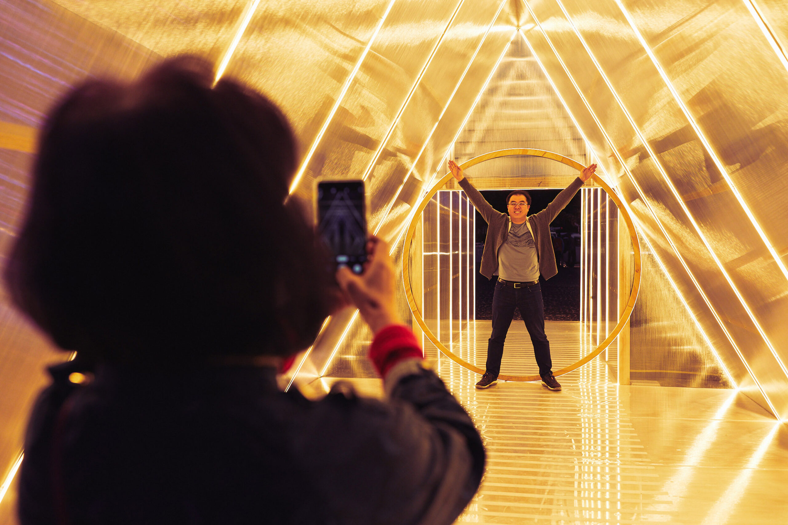 A person is photographed inside a brightly lit triangular tunnel