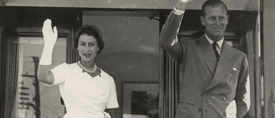 Queen Elizabeth and Prince Philip wave from the back of a tram