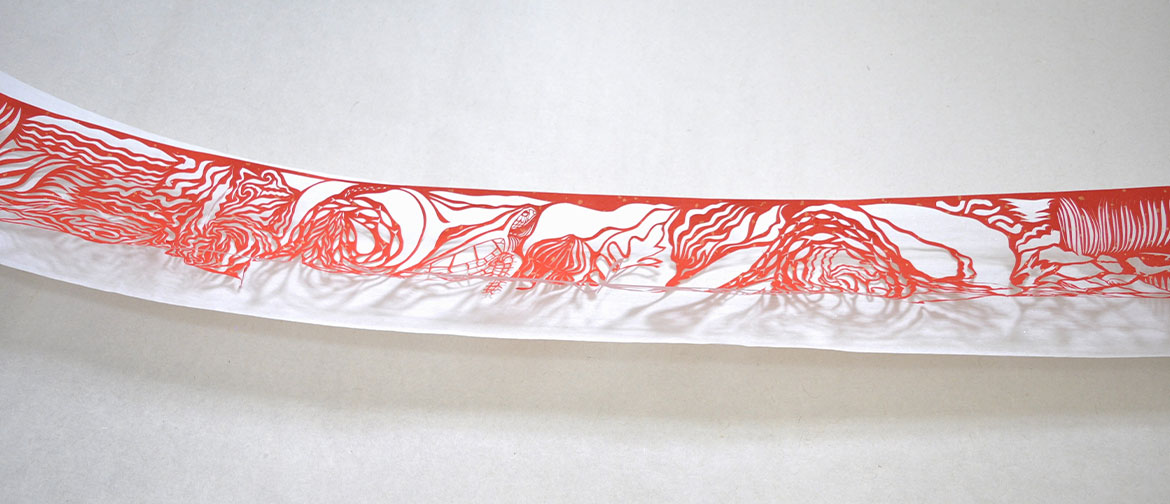 Intricate red paper cutout on a length of white rice paper