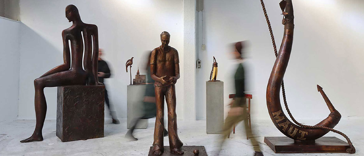 Blurred people stride past large bronze sculptures.