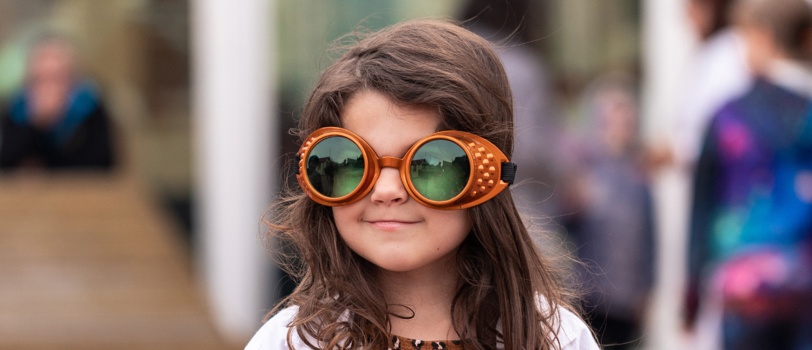 photograph of little girl wearing lab coat and oversize goggles at a social event