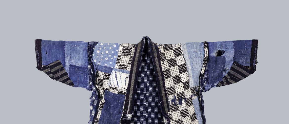 photograph of japanese boro style garment on plain blue-grey background