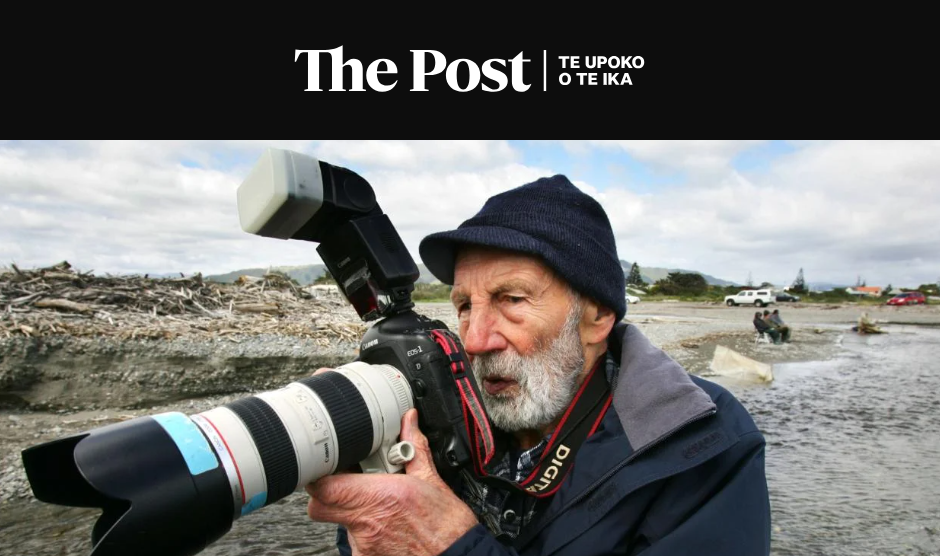 Image of an elderly man wearing a beanie, holding a large camera